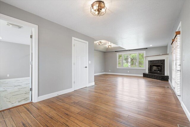 101 Poindexter Dr, Pineville, MO 64856 - unfurnished living room with a tiled fireplace, hardwood / wood-style floors, visible vents, and baseboards