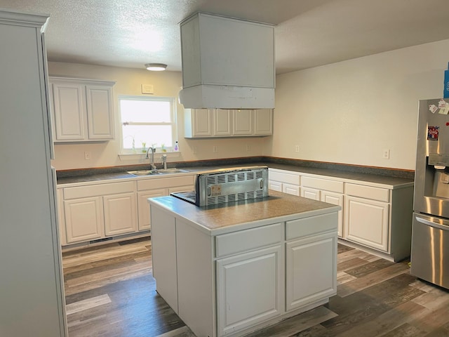 kitchen with stainless steel refrigerator with ice dispenser, a center island, dark wood-style floors, and a sink