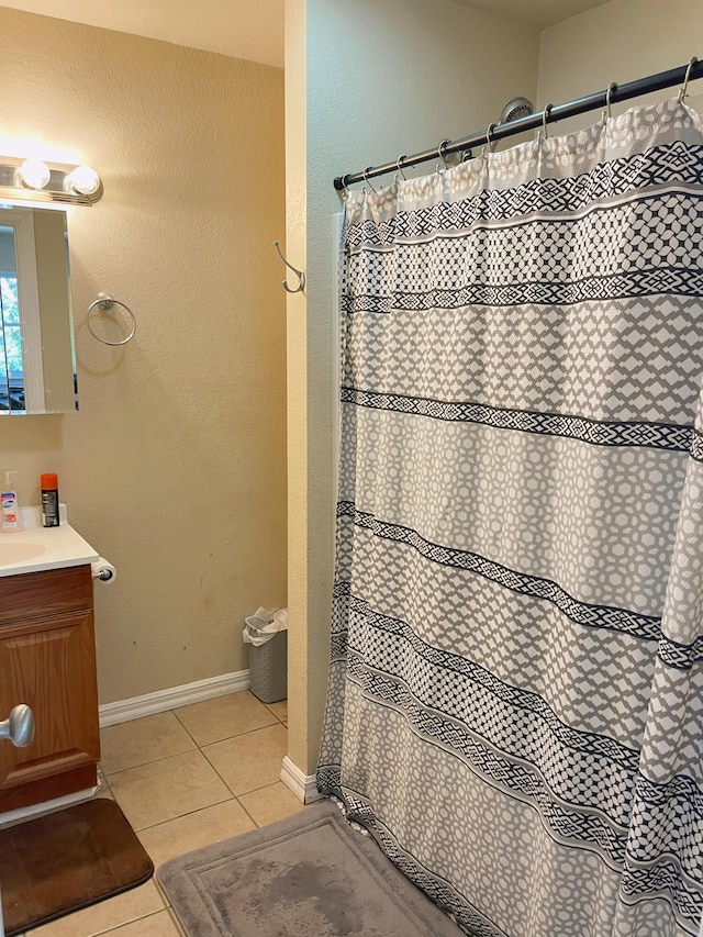 bathroom featuring baseboards, vanity, tile patterned floors, and curtained shower