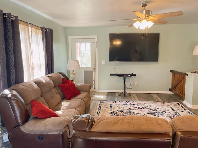 living area featuring baseboards, a ceiling fan, and wood finished floors