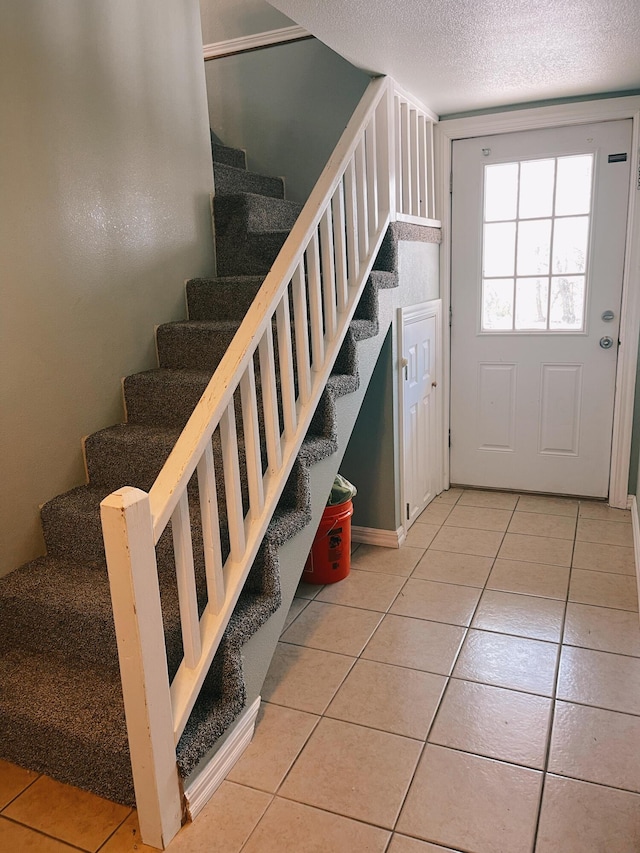 stairway featuring tile patterned flooring and a textured ceiling