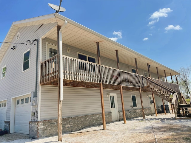 rear view of house featuring a garage, central AC unit, stairway, and a deck