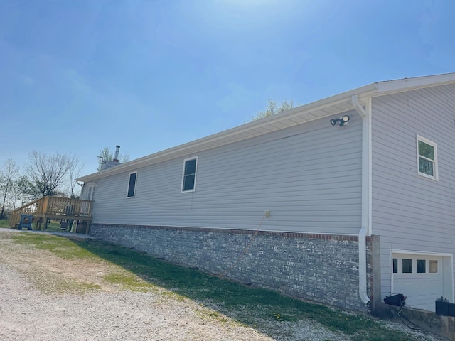 view of home's exterior with an attached garage and a wooden deck