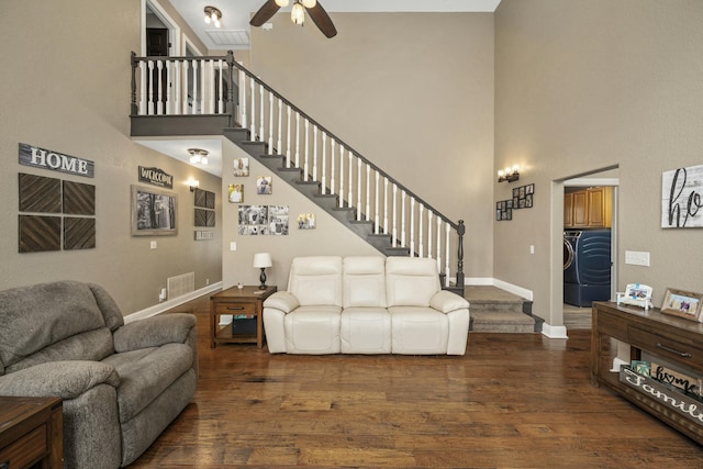 living area featuring a ceiling fan, wood finished floors, stairs, baseboards, and a high ceiling