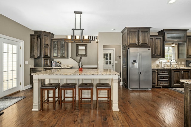 kitchen with dark brown cabinetry, high quality fridge, light stone countertops, and dark wood-style floors