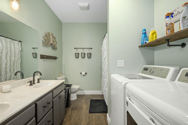 laundry area featuring washing machine and clothes dryer, a sink, laundry area, and dark wood finished floors