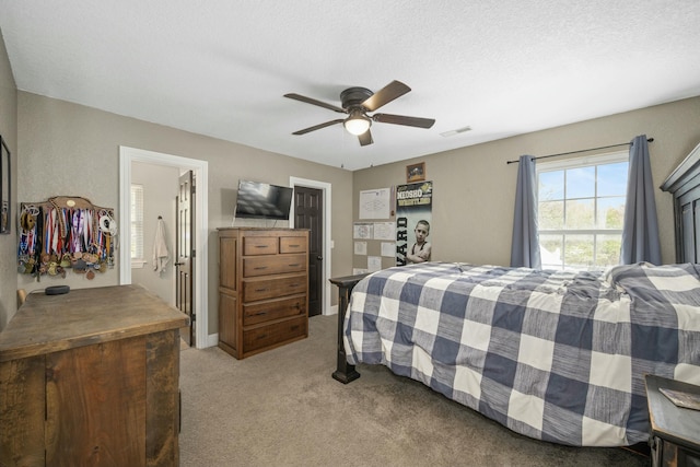 bedroom with a textured ceiling, visible vents, a ceiling fan, and light colored carpet