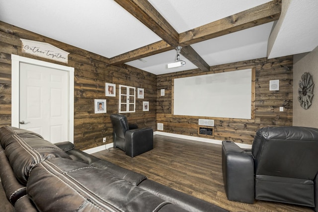 home theater room with baseboards, wood walls, wood finished floors, and beamed ceiling