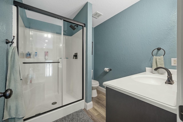 full bath with toilet, visible vents, wood finished floors, a shower stall, and a textured wall