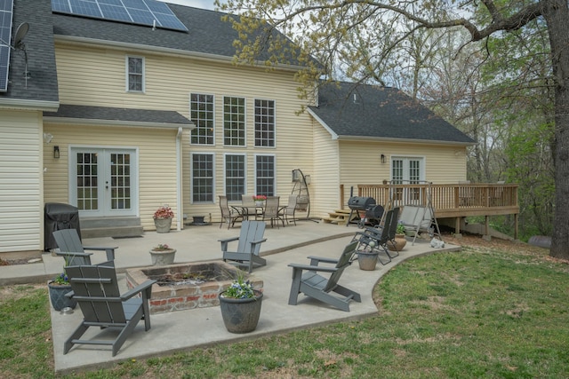 back of house with french doors, roof with shingles, and an outdoor fire pit