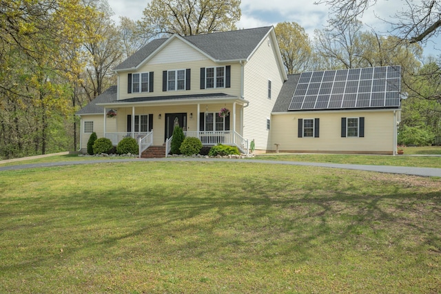 view of front facade with roof mounted solar panels, a front lawn, covered porch, and roof with shingles