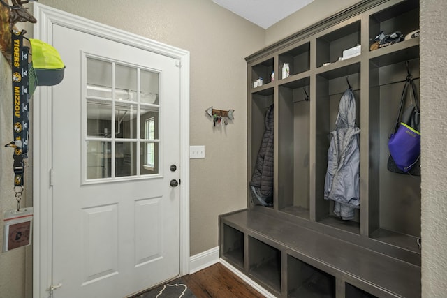 mudroom featuring baseboards, a textured wall, and dark wood-type flooring