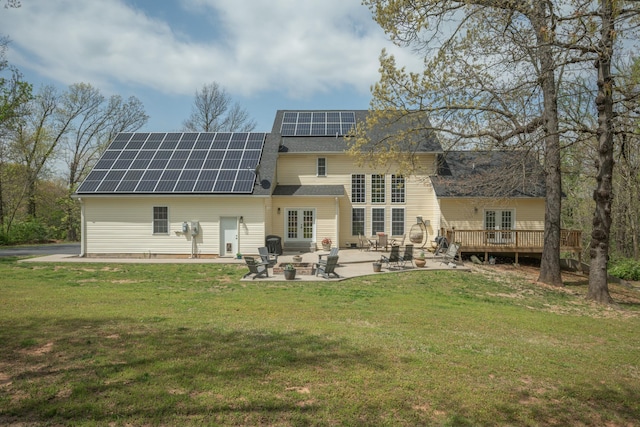 back of property featuring roof mounted solar panels, a lawn, french doors, and a patio area
