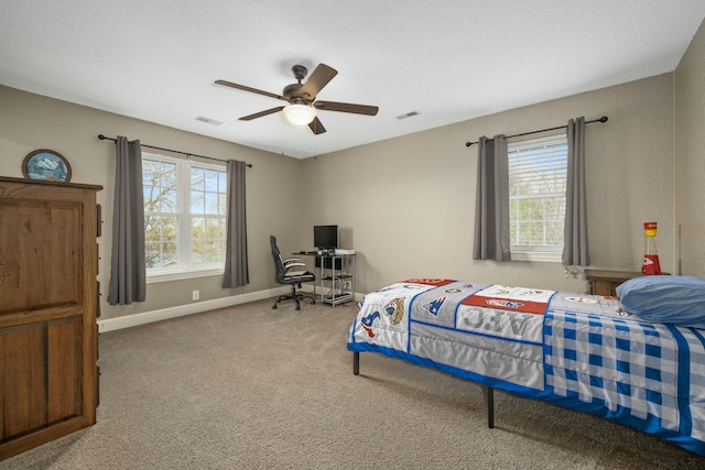 carpeted bedroom featuring baseboards, visible vents, ceiling fan, and multiple windows