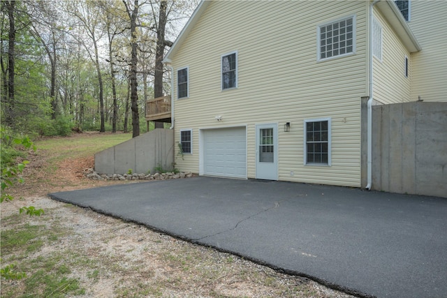 view of property exterior featuring aphalt driveway, a deck, and a garage