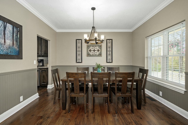dining area with wainscoting, wood finished floors, an inviting chandelier, and ornamental molding