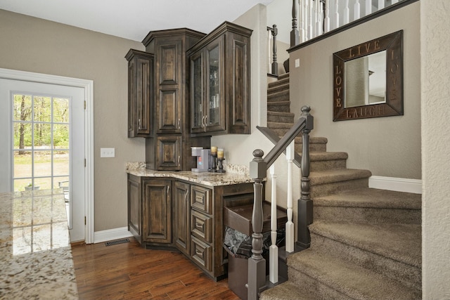 bar featuring dark wood-type flooring, stairs, baseboards, and visible vents