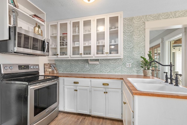 344 Zinnia Ln, Kirbyville, MO 65679 - kitchen featuring appliances with stainless steel finishes, wallpapered walls, a sink, white cabinets, and light wood finished floors