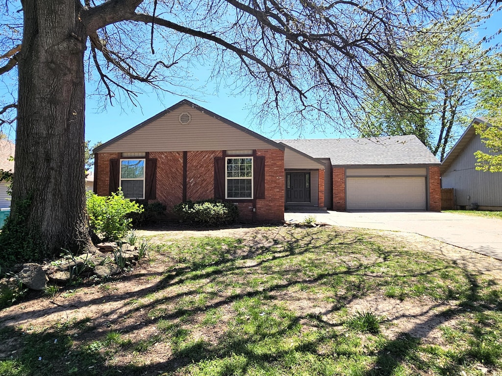 ranch-style house with brick siding, an attached garage, and driveway