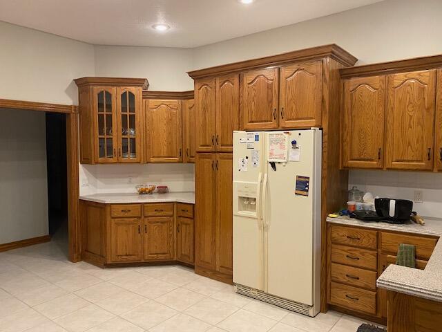4822 S Montrose Pl, Springfield, MO 65810 - kitchen with brown cabinetry, glass insert cabinets, white refrigerator with ice dispenser, and light countertops