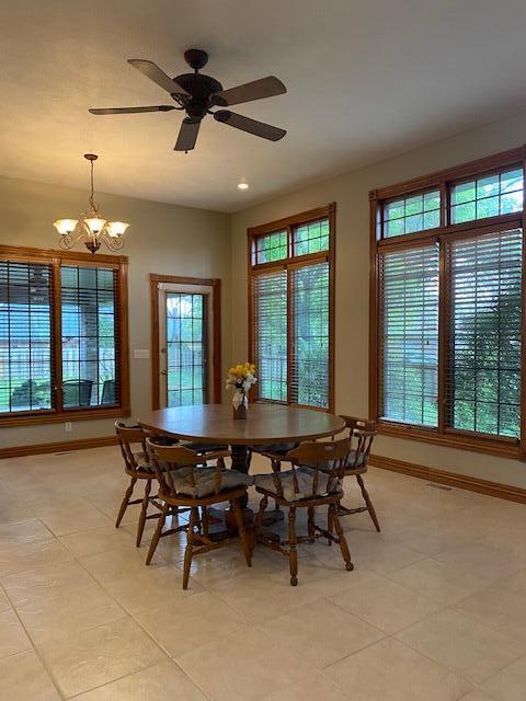 4822 S Montrose Pl, Springfield, MO 65810 - dining room with baseboards, a wealth of natural light, ceiling fan with notable chandelier, and light tile patterned floors