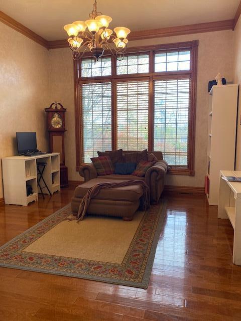 4822 S Montrose Pl, Springfield, MO 65810 - living area featuring baseboards, wood finished floors, an inviting chandelier, and crown molding