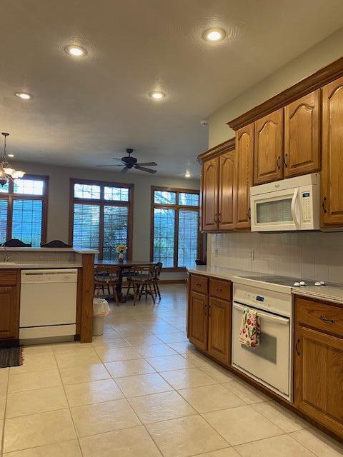 4822 S Montrose Pl, Springfield, MO 65810 - kitchen with recessed lighting, backsplash, white appliances, brown cabinetry, and ceiling fan with notable chandelier
