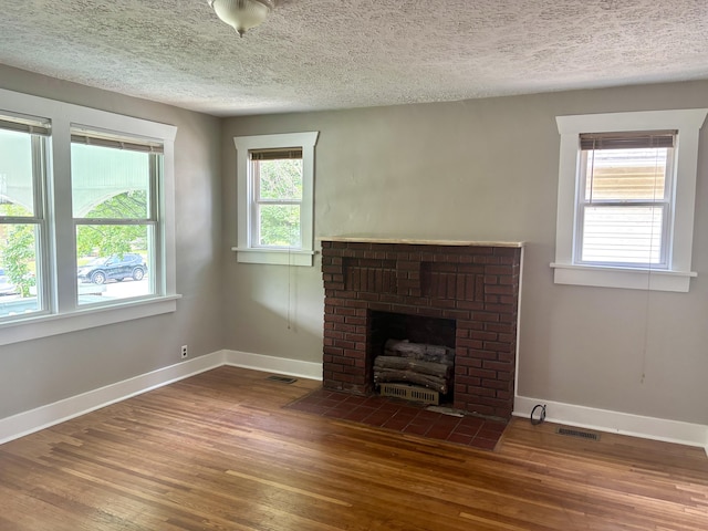 535 E Normal St, Springfield, MO 65807 - unfurnished living room with wood finished floors, a brick fireplace, and a textured ceiling