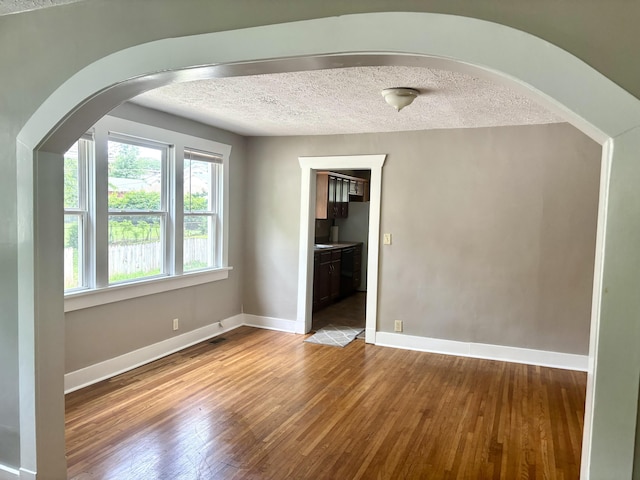 535 E Normal St, Springfield, MO 65807 - empty room featuring hardwood / wood-style flooring, arched walkways, and a textured ceiling