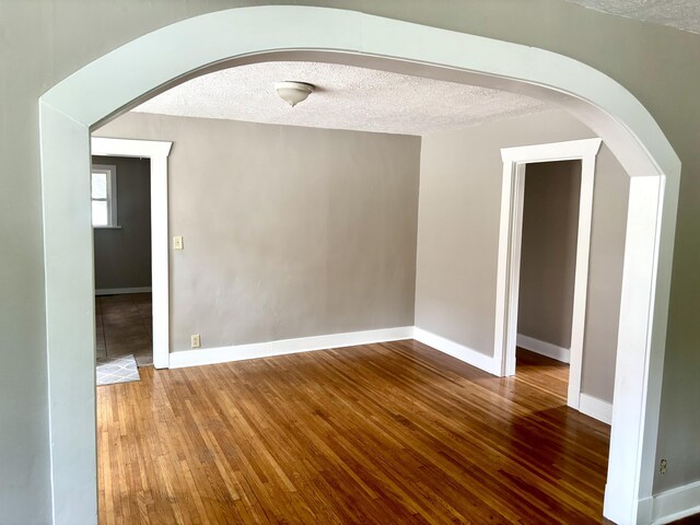 535 E Normal St, Springfield, MO 65807 - spare room with hardwood / wood-style floors, arched walkways, and a textured ceiling