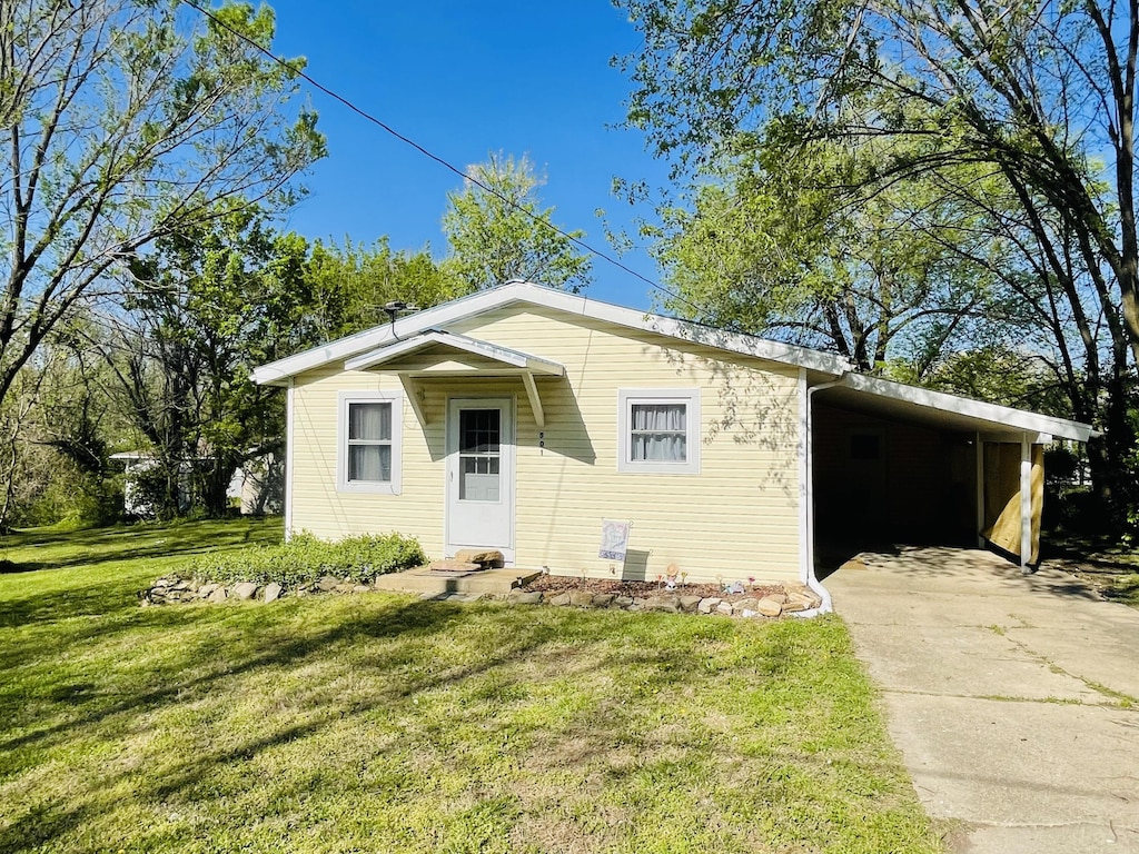 bungalow-style home featuring concrete driveway, a carport, and a front yard