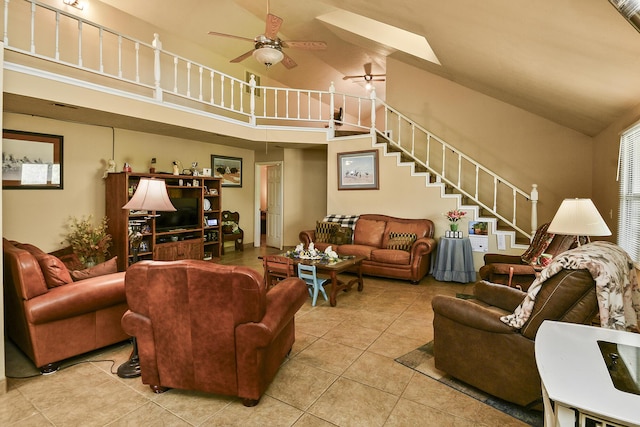 living area with light tile patterned floors, a ceiling fan, high vaulted ceiling, and stairway