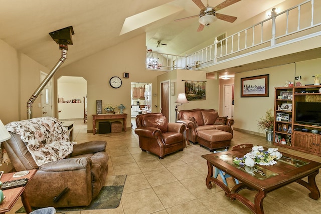 living room featuring light tile patterned flooring, arched walkways, a ceiling fan, and high vaulted ceiling