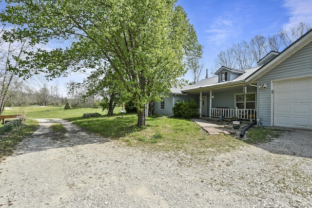 view of side of home featuring a garage, a yard, driveway, and covered porch