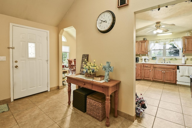 entryway featuring ceiling fan, arched walkways, baseboards, and light tile patterned floors