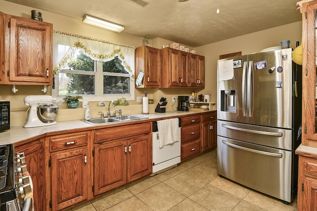kitchen with a sink, brown cabinetry, light tile patterned floors, stainless steel appliances, and light countertops