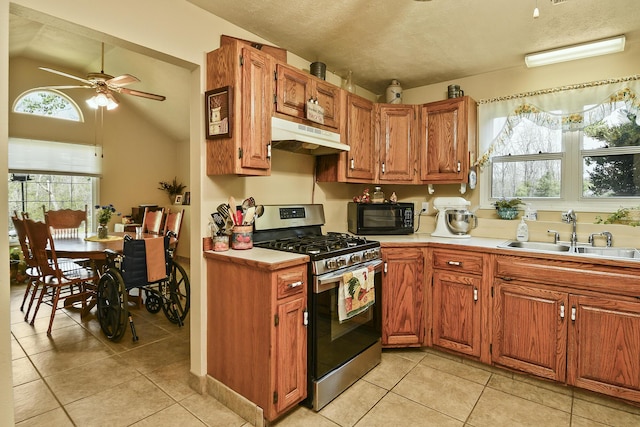 kitchen featuring under cabinet range hood, light countertops, a sink, black microwave, and gas stove