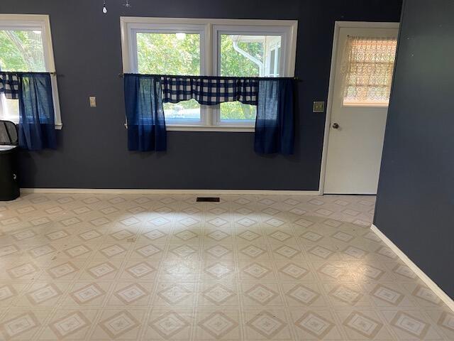 unfurnished room with visible vents, baseboards, and a wealth of natural light