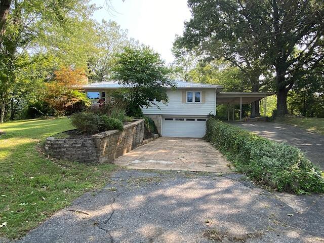 view of front of house with a garage, driveway, a front lawn, and a carport