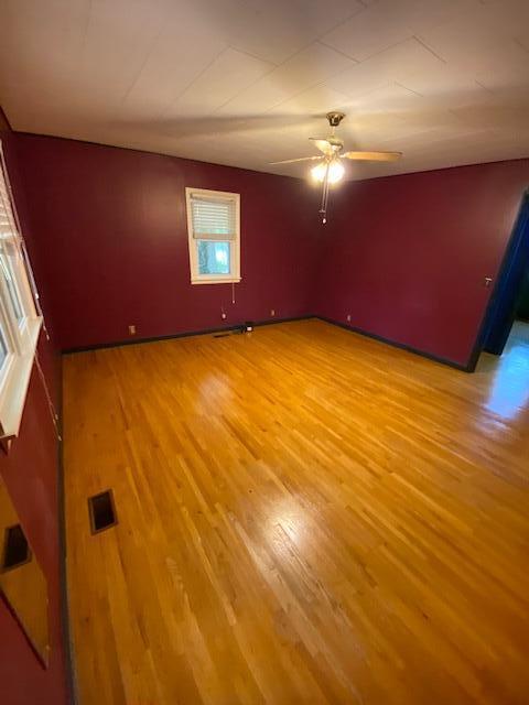 empty room with light wood-type flooring, visible vents, and ceiling fan