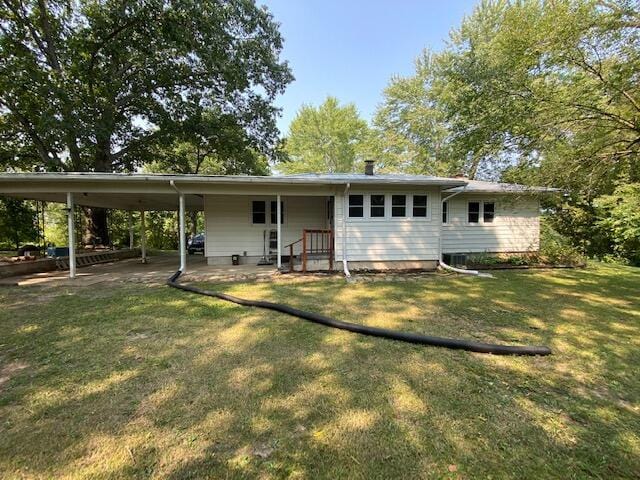 back of property featuring a lawn and an attached carport