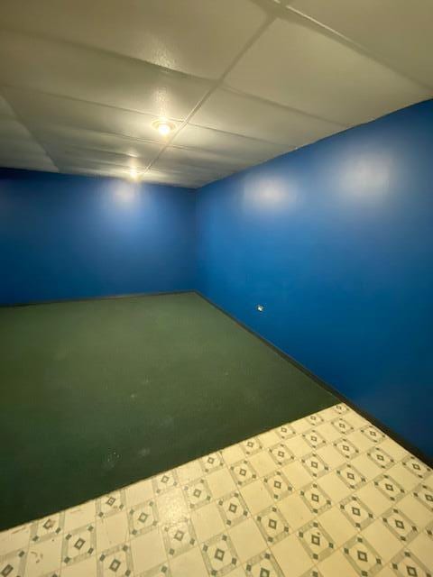 interior space featuring carpet flooring, tile patterned floors, and a paneled ceiling