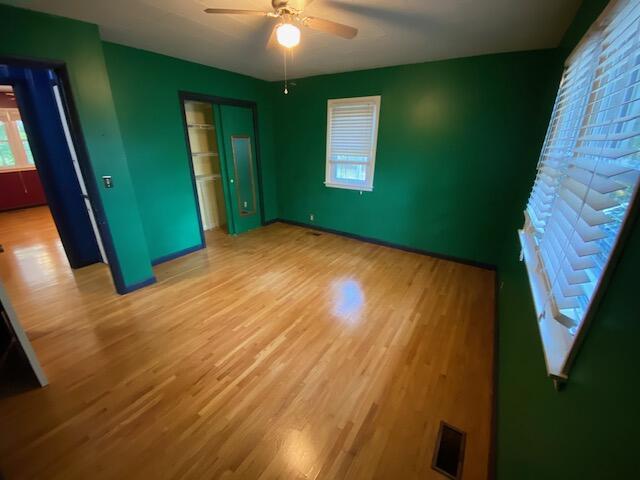 unfurnished bedroom featuring baseboards, light wood-style flooring, visible vents, and a closet