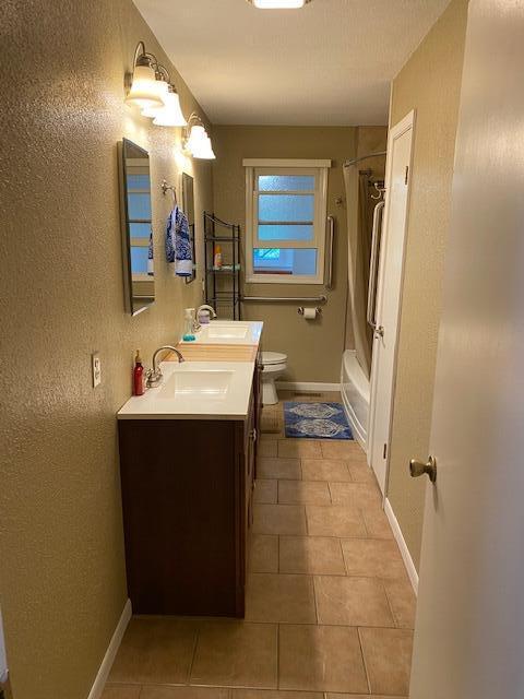 full bathroom with shower / bathing tub combination, tile patterned flooring, toilet, and a sink