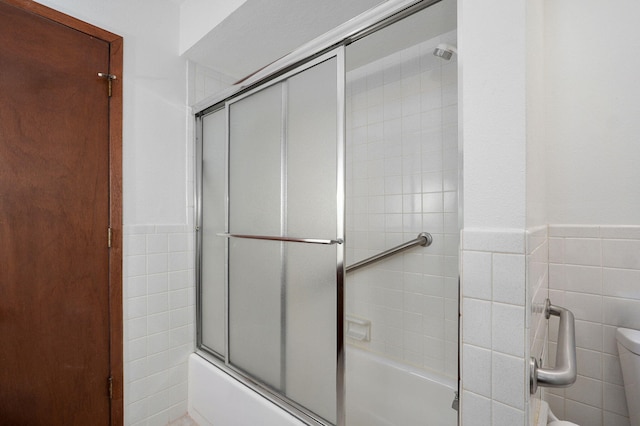 4542 S Holiday Ave, Springfield, MO 65810 - full bath featuring tile walls, combined bath / shower with glass door, wainscoting, and toilet
