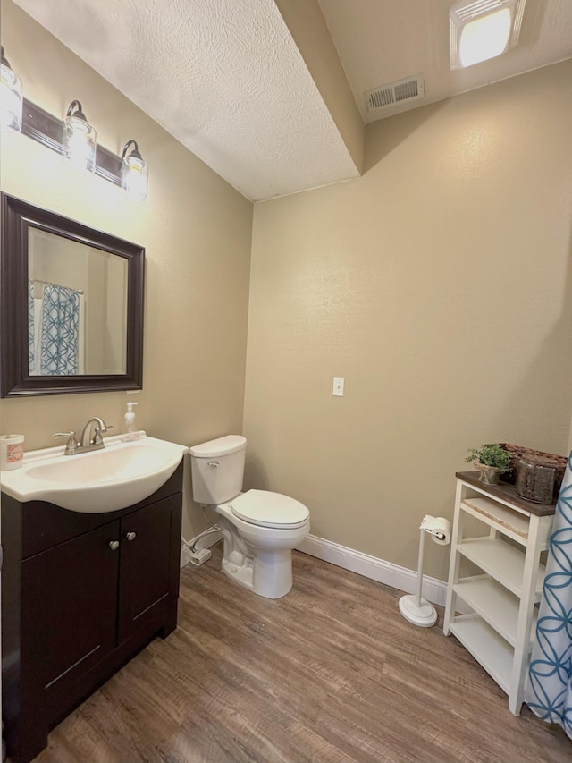 full bath featuring vanity, baseboards, toilet, visible vents, and wood finished floors