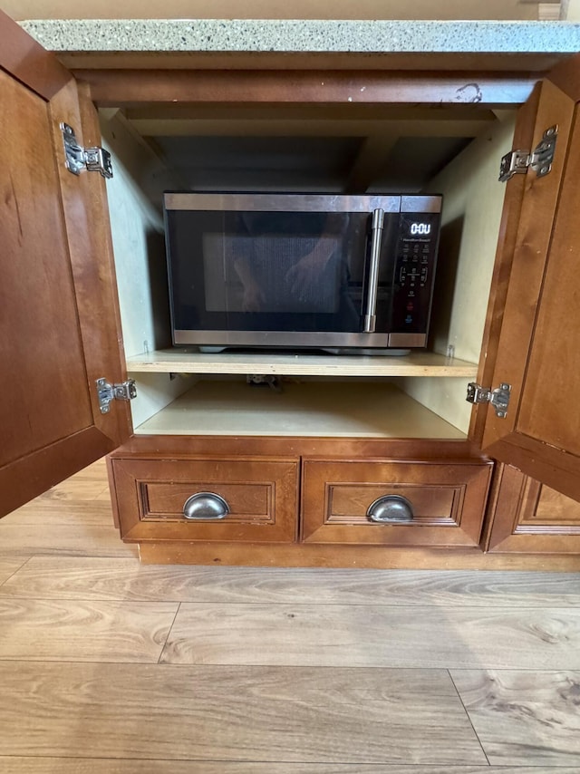details featuring brown cabinetry and stainless steel microwave