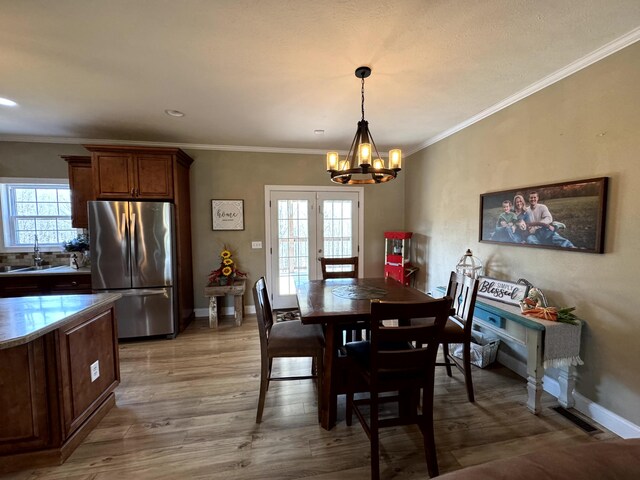 dining area with wood finished floors, baseboards, ornamental molding, and an inviting chandelier