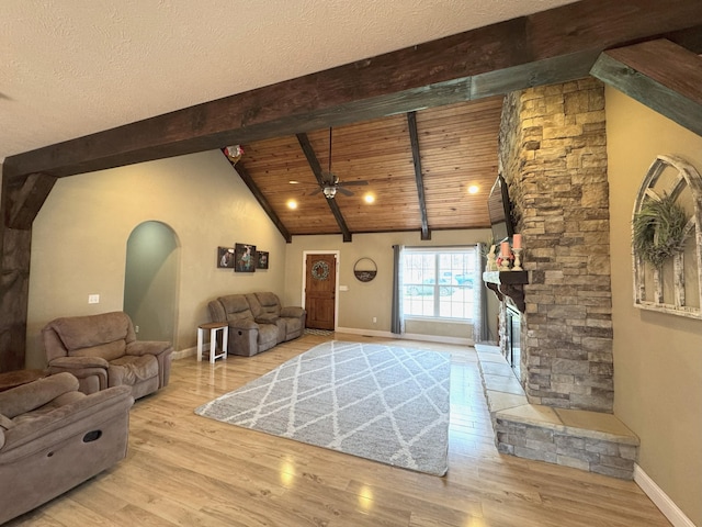 living room featuring vaulted ceiling with beams, baseboards, a ceiling fan, and wood finished floors