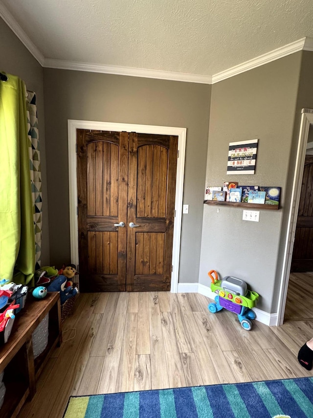 foyer with baseboards, wood finished floors, a textured ceiling, and crown molding